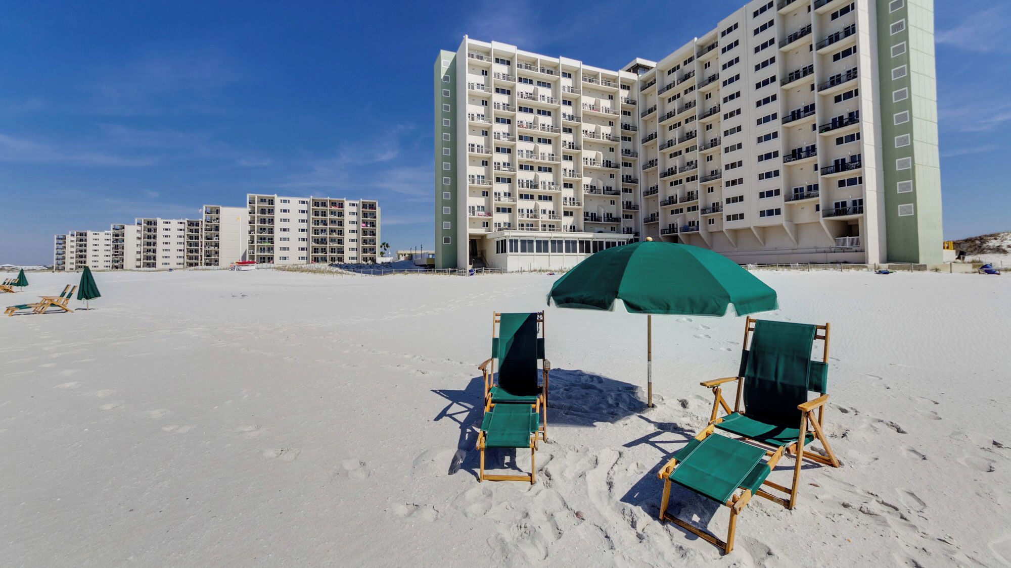 A beachfront hotel with multiple high-rise buildings, beach chairs, and umbrellas.