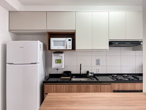 A modern kitchen with a refrigerator, microwave, and stove.