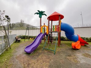 A playground with a slide, climbing area, and a small shelter.