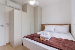 A hotel room with a bed, a wardrobe, and an air conditioning unit.
