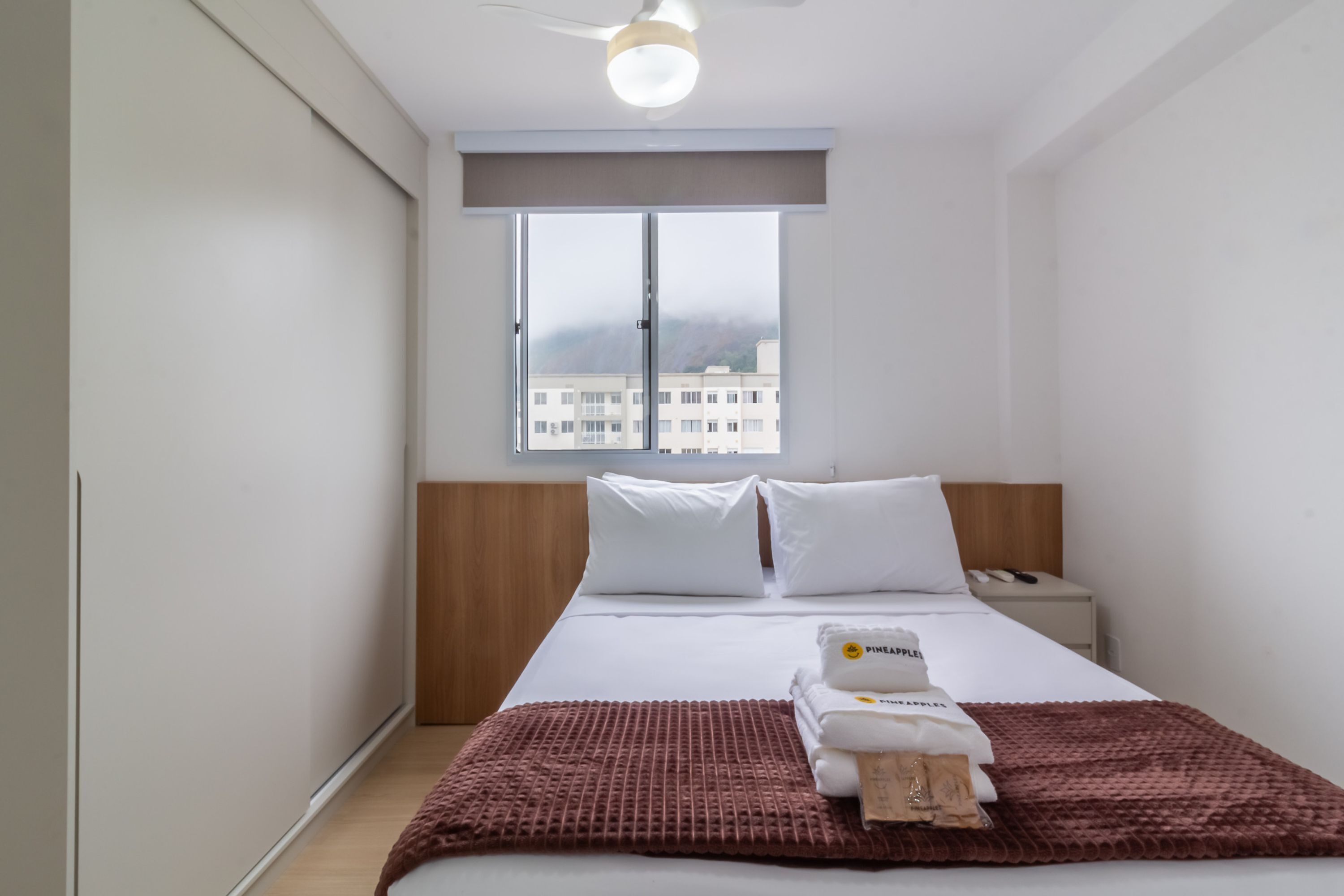 Una camera d'albergo con un letto, una finestra, un comodino e un tavolino.