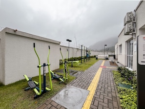 An outdoor exercise area with stationary bikes and a paved path with tactile paving for the visually impaired.