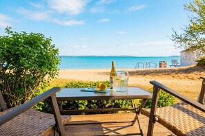 Ein Tisch mit einer Flasche und einem Krug auf einer Terrasse mit Blick auf einen Strand.