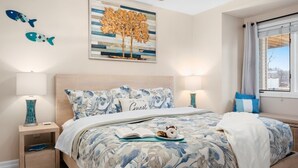 Una camera da letto con un letto, due comodini, una lampada da comodino, una finestra con tende e decorazioni murali.