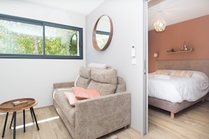 A modern room with a sofa, a small round table, a bed, and a large window. - Les Nids des Mûriers (2-person) (CHAPAREILLAN)