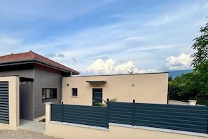 A modern two-story house with a garage, a small front porch, and a green fence. - Les Nids des Mûriers (2-person) (CHAPAREILLAN)