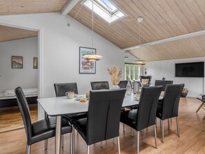 Un espace repas doté d’un plafond haut, d’une verrière et de mobilier moderne.