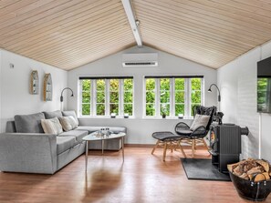 A modern living room with a grey sofa, a coffee table, a fireplace, and a large window with a view of greenery. - "Tian" - 1km from the sea by Interhome (Skagen)
