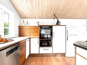 Una cocina moderna con armarios de madera, horno empotrado y lavavajillas.