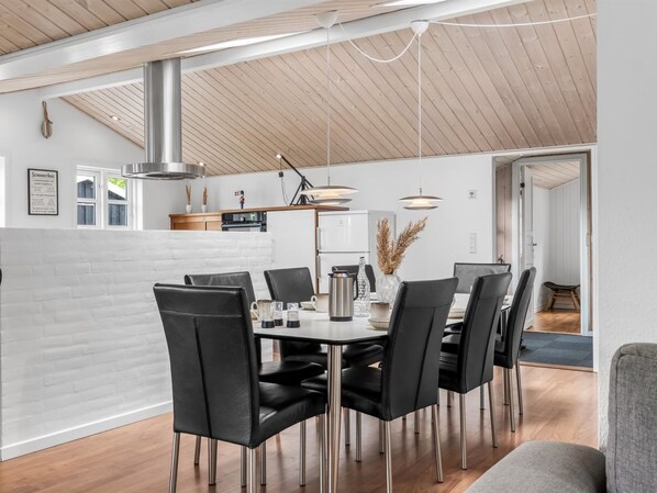 A modern kitchen with a central island, stainless steel appliances, and a dining area with black chairs and a wooden table.