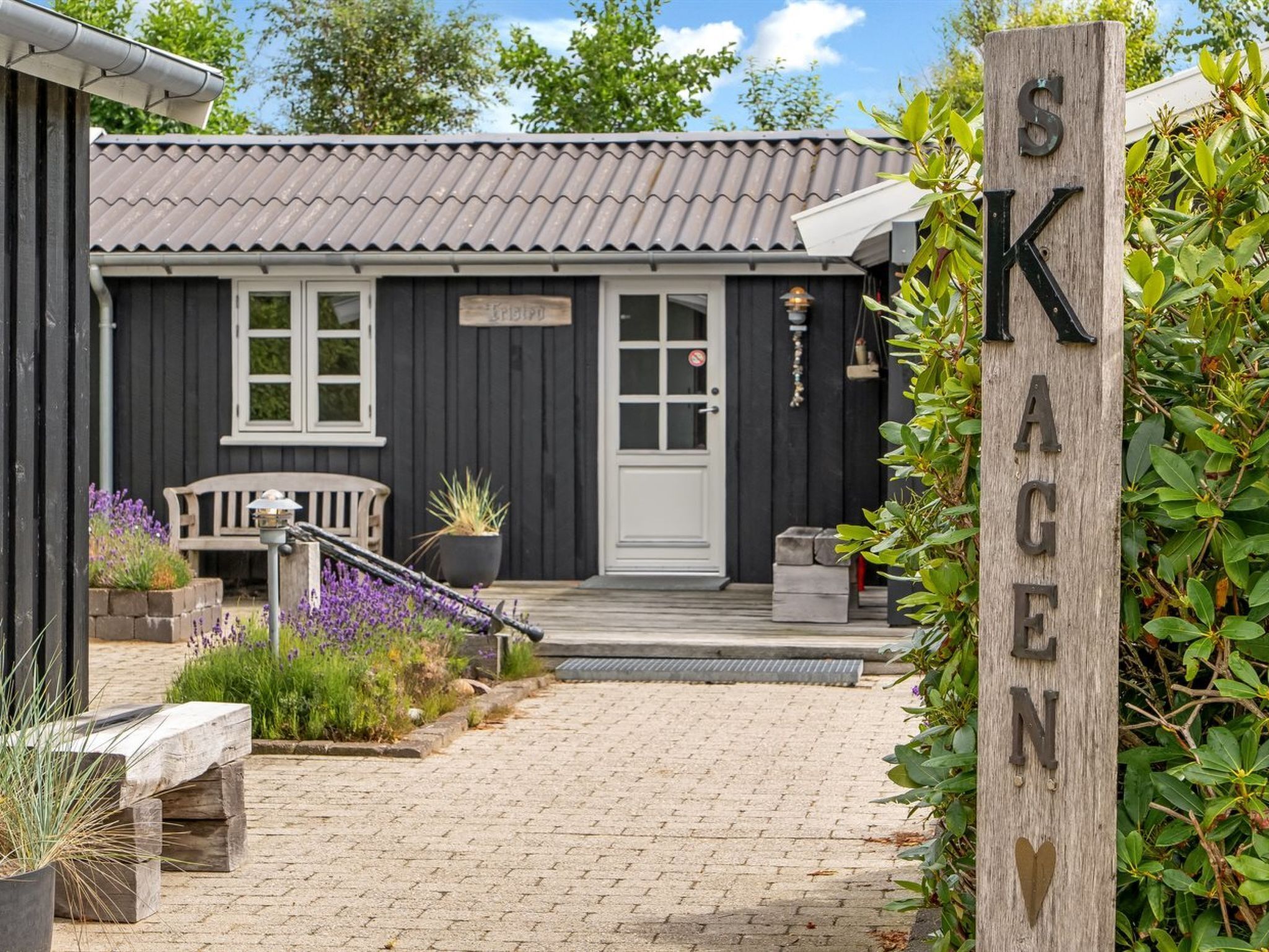 A black building with a tiled roof, a white door, and a sign reading 'SKAGEN'.