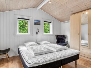 Une chambre à coucher avec un lit, deux fenêtres, une chaise et une armoire.