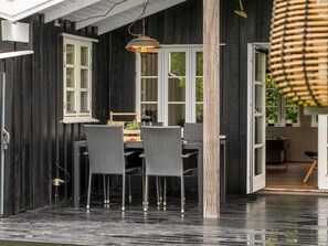 A dining area with a table and chairs, a hanging light fixture, and a view of the outdoors.