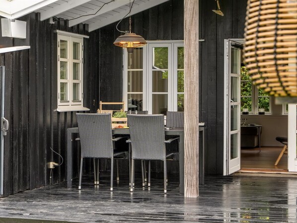 Un espace repas comprenant une table et des chaises, un luminaire suspendu et une vue sur l’extérieur.