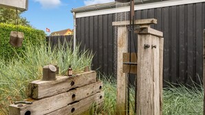 A wooden structure with a water spout, a flag, and a fence in the background.