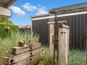 A wooden structure with a water spout, a flag, and a fence in the background.