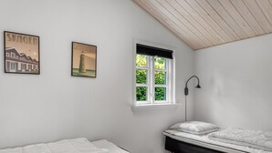 A bedroom with two beds, a window with blinds, and two wall-mounted pictures.