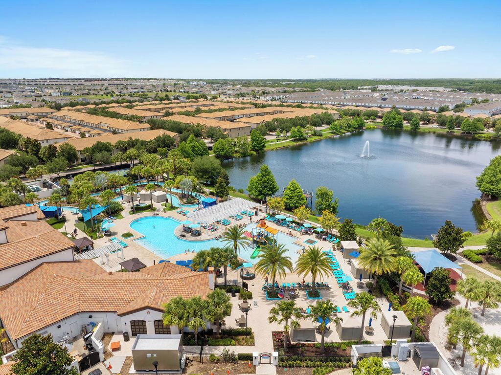 Un complexe hôtelier doté d’une grande piscine, de palmiers et offrant une vue sur un lac.