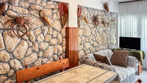 Una sala de estar con una pared de piedra, un banco de madera, un sofá y un televisor.