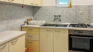 Una cocina con estufa a gas, pileta doble y horno empotrado.