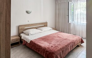 A bedroom with a wooden headboard, a bed with white bedding, a nightstand, and a window with curtains. - Stunning apartment in Lopar with house sea view (Lopar)