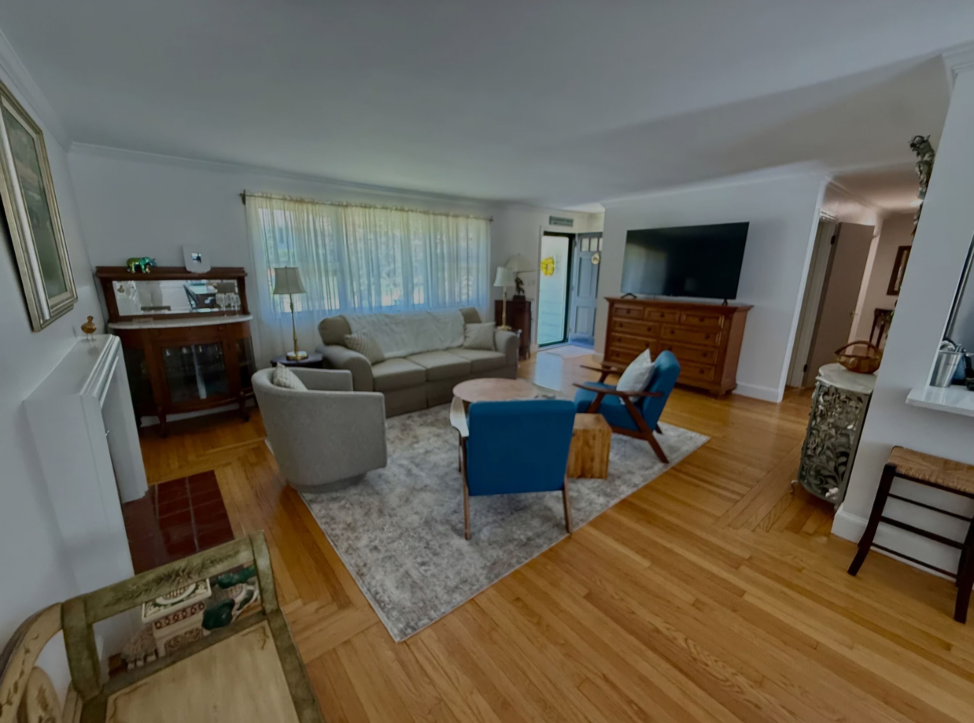 A living room with a sofa, armchairs, a coffee table, and a TV.