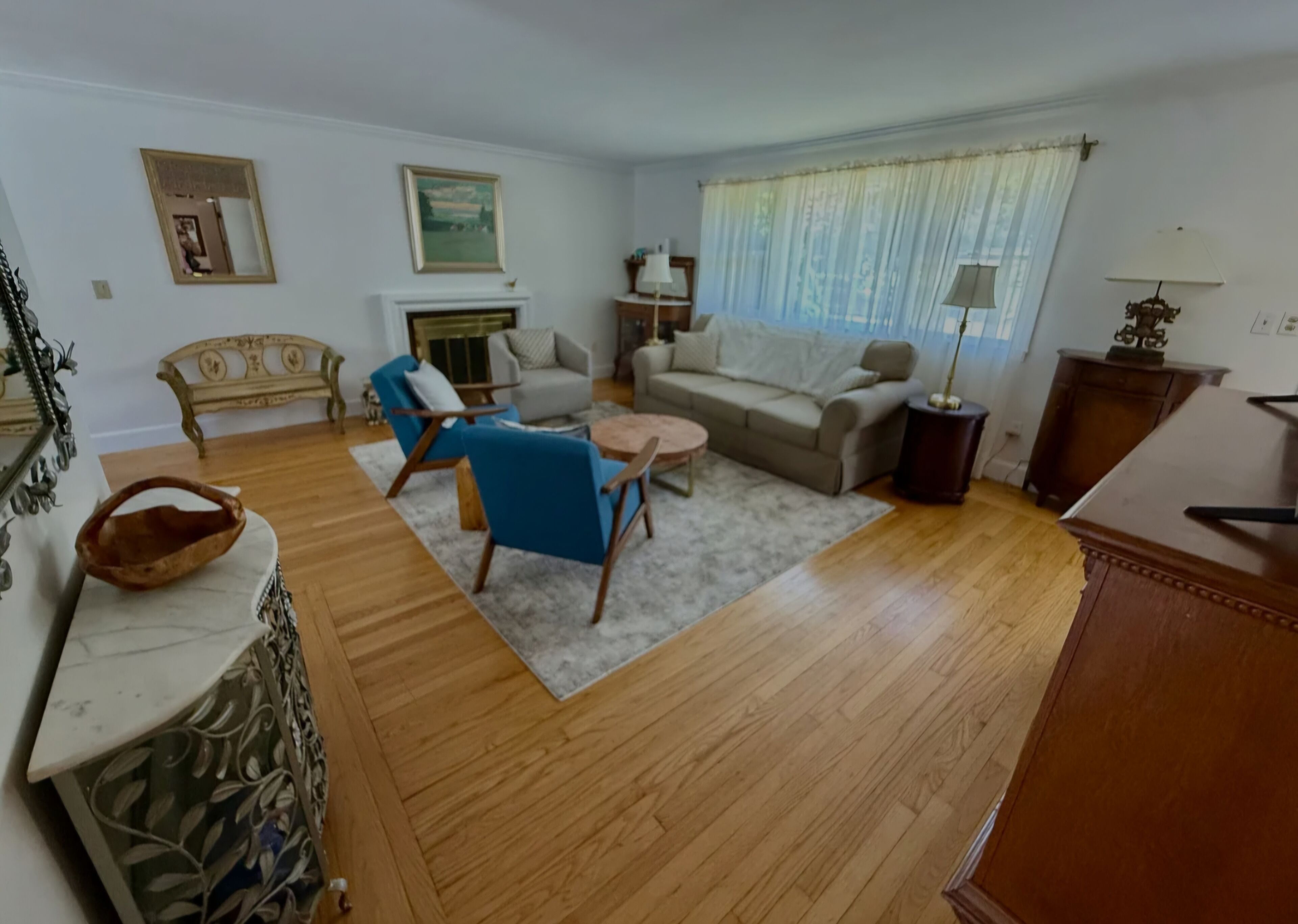 A living room with a fireplace, a sofa, a blue armchair, and a wooden coffee table.