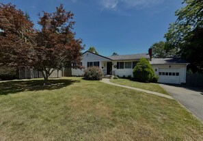 A residential house with a front yard, a driveway, and a garage. - Perfect 5-bedroom house with AC in delightful Newport (Newport)