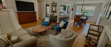A spacious living room with a sofa, armchairs, a coffee table, and a TV.