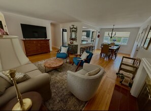 A spacious living room with a sofa, armchairs, a coffee table, and a TV. - Perfect 5-bedroom house with AC in delightful Newport (Newport)