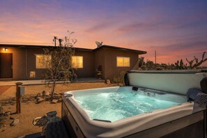 Ein Whirlpool mit Blick auf ein Haus und eine Wüstenlandschaft im Abenddämmerung.