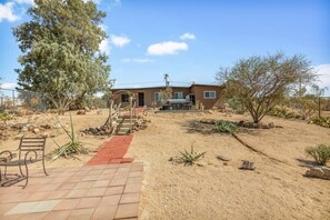 Ein Haus mit befestigter Auffahrt, die zu einer Haustür führt, umgeben von trockener Vegetation und einem klaren Himmel.
