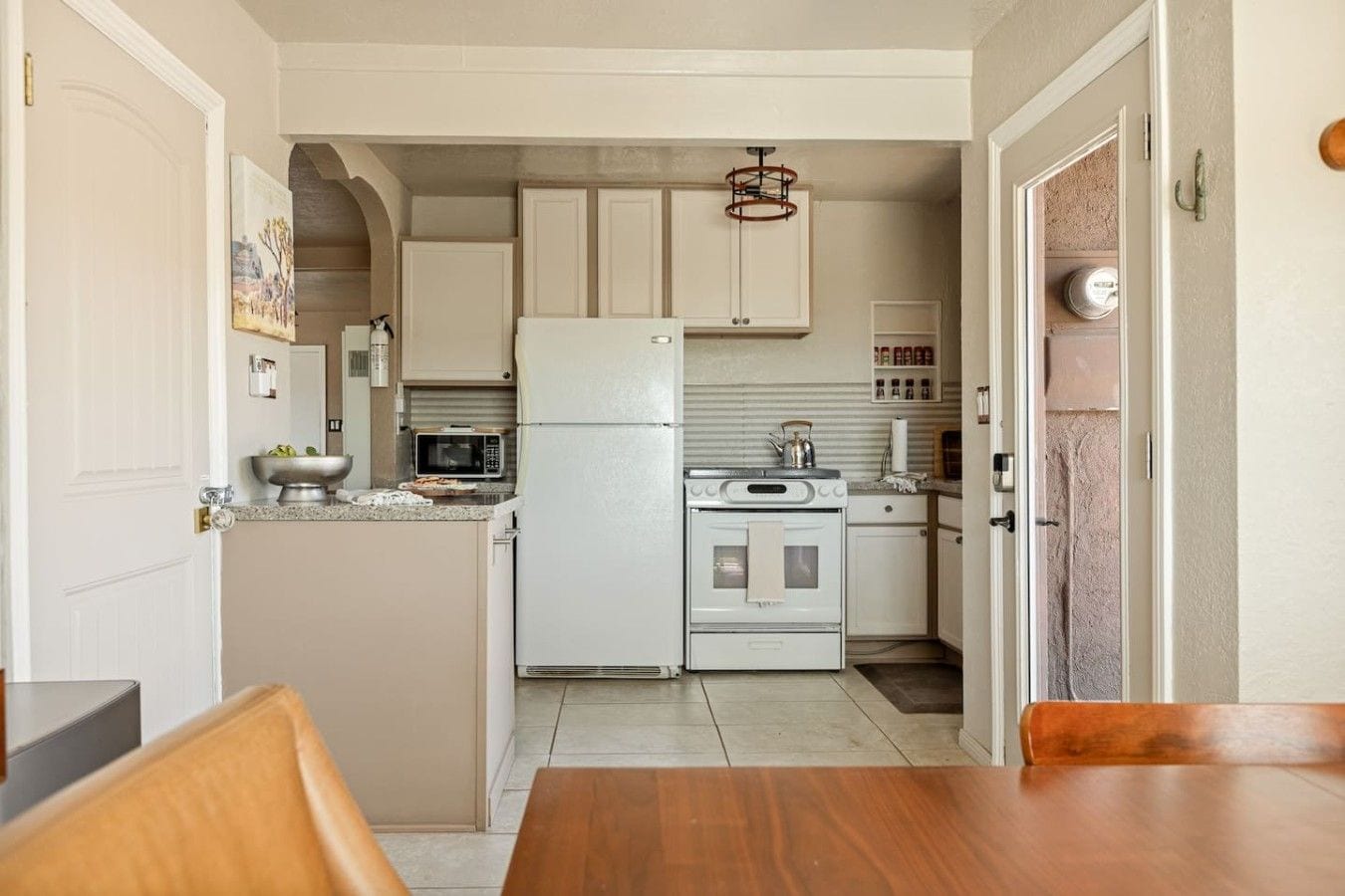 A compact kitchen with white cabinets, a microwave, a stove, and a refrigerator.