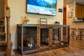 Una jaula de madera para perro con un televisor encima que muestra un paisaje montañoso.
