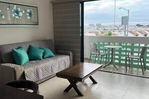 A modern living room with a sofa, coffee table, and a balcony with a view. - Javier | Diana | Mazatlan (Mazatlan)