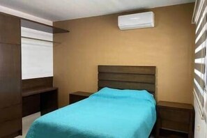 A bedroom with a bed, bedside tables, a window with blinds, and an air conditioning unit. - Javier | Diana | Mazatlan (Mazatlan)
