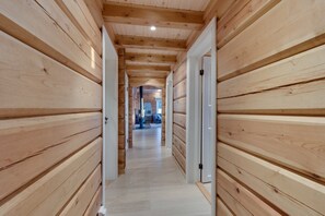 A wooden hallway with doors leading to a room with a window.