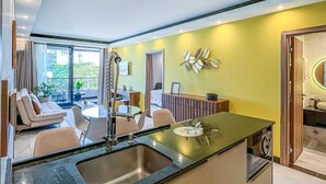 A modern kitchen with a central island, a dining area with a sofa and chairs, and a view of the outdoors.