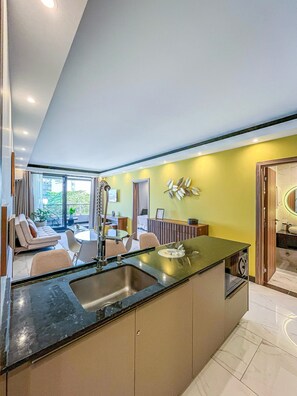 A modern kitchen with a central island, a dining area with a sofa and chairs, and a view of the outdoors.
