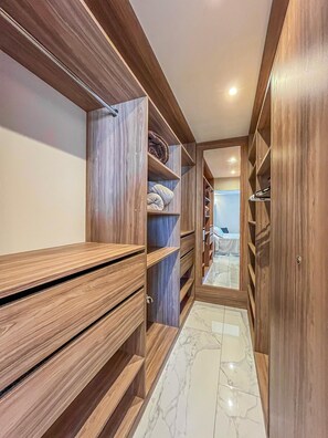 A walk-in closet with wooden shelving and drawers, marble flooring, and a view into a bedroom with a bed and nightstand. - Cozy & elegante 2-bedroom apartment (Santa Cruz de la Sierra)