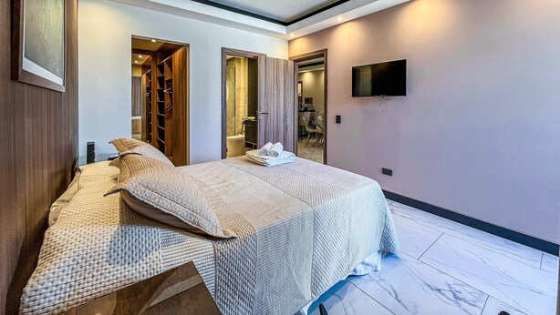 A hotel room with a bed, a TV, a bathroom, and a seating area.