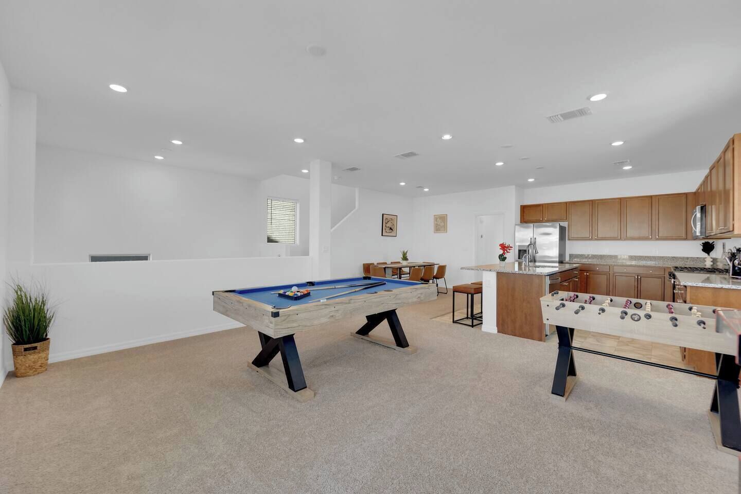 Un espace de vie moderne comprenant une table de billard, un baby-foot, un coin cuisine et un coin repas.