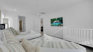 Ein Schlafzimmer mit einem Bett, einem weißen Babybett und einem an der Wand befestigten Fernseher.