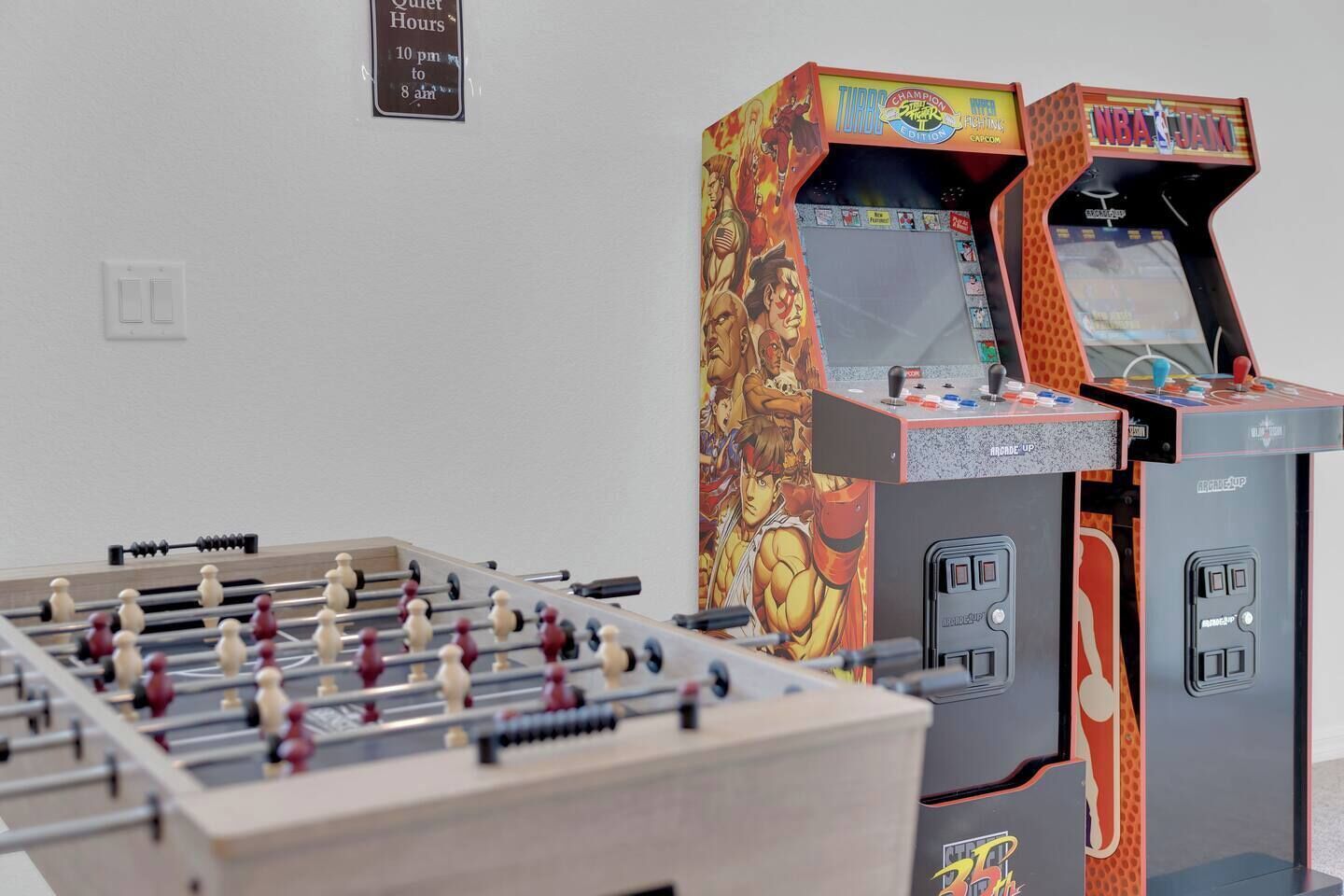 Une table de baby-foot et deux bornes d’arcade dans une pièce.
