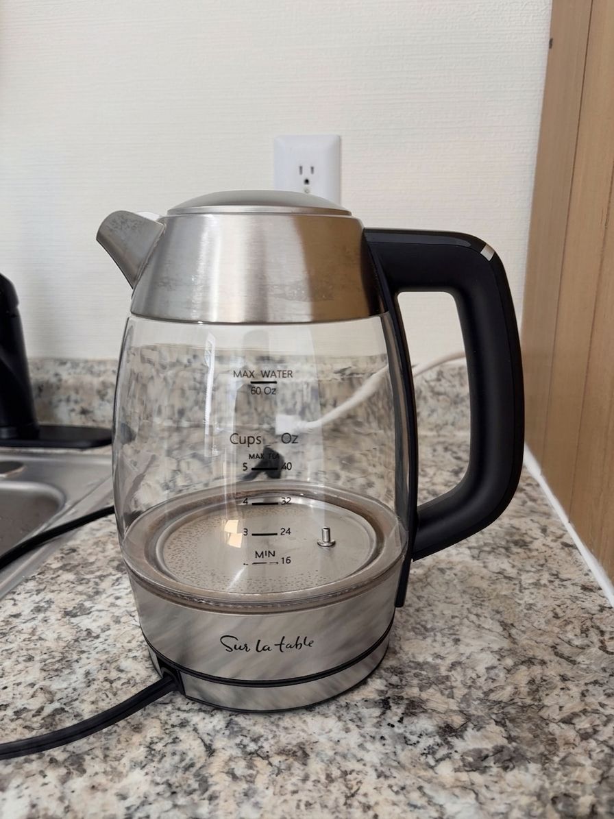 En gennemsigtig elkedel af glas med måleskalaer på en granitbordplade.