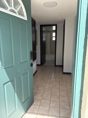 A hallway with a door leading to a bathroom, a tiled floor, and a ceiling light fixture. - Private 1-Bedroom Studio with Parking Near Orlando (Orlando)
