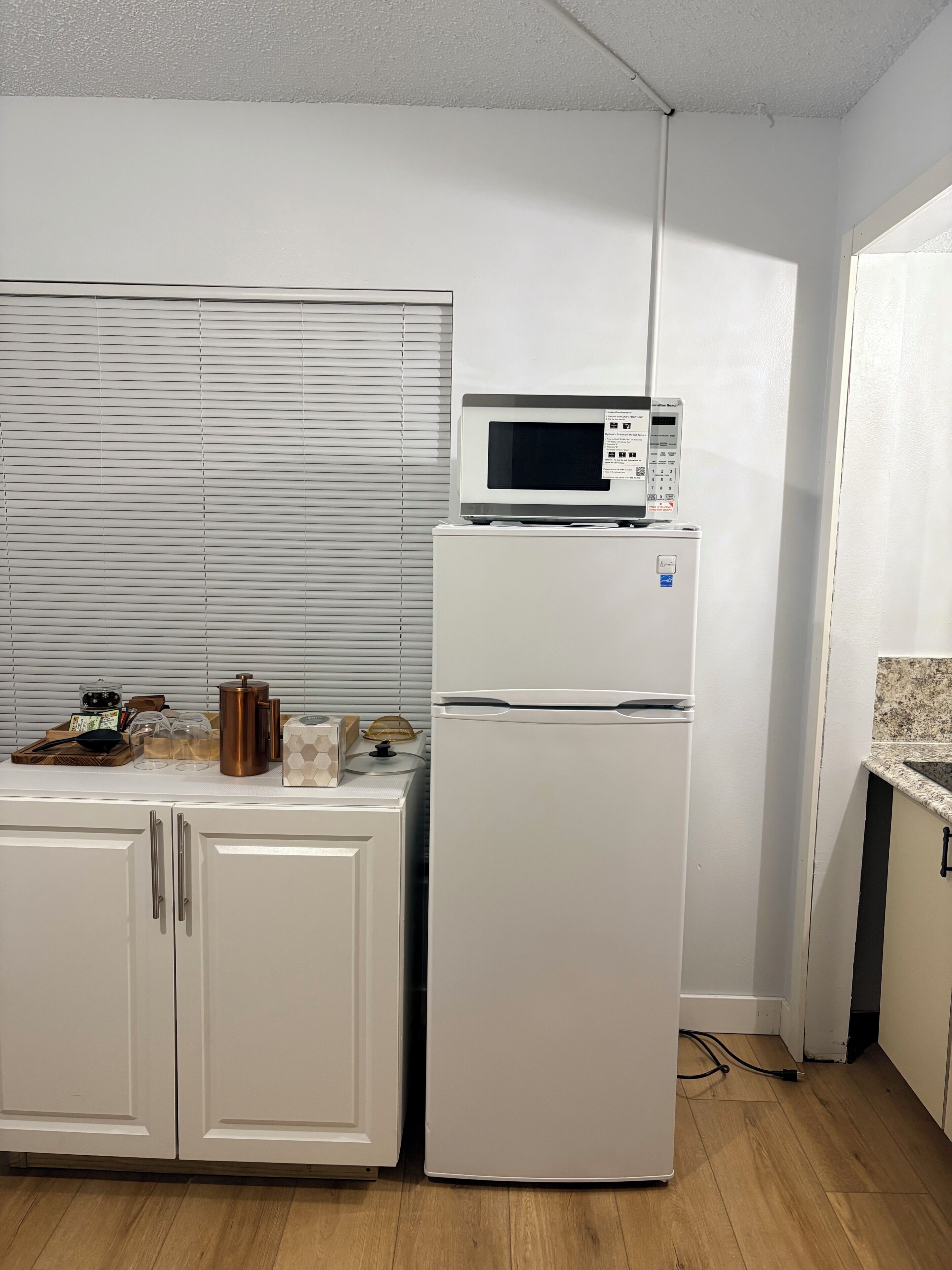 Une cuisine avec un réfrigérateur blanc, un four à micro-ondes et un plan de travail en bois sur lequel sont disposés divers objets.