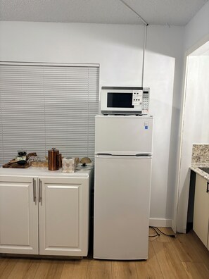 A kitchen with a white refrigerator, a microwave, and a wooden countertop with various items. - Private 1-Bedroom Studio with Parking Near Orlando (Orlando)
