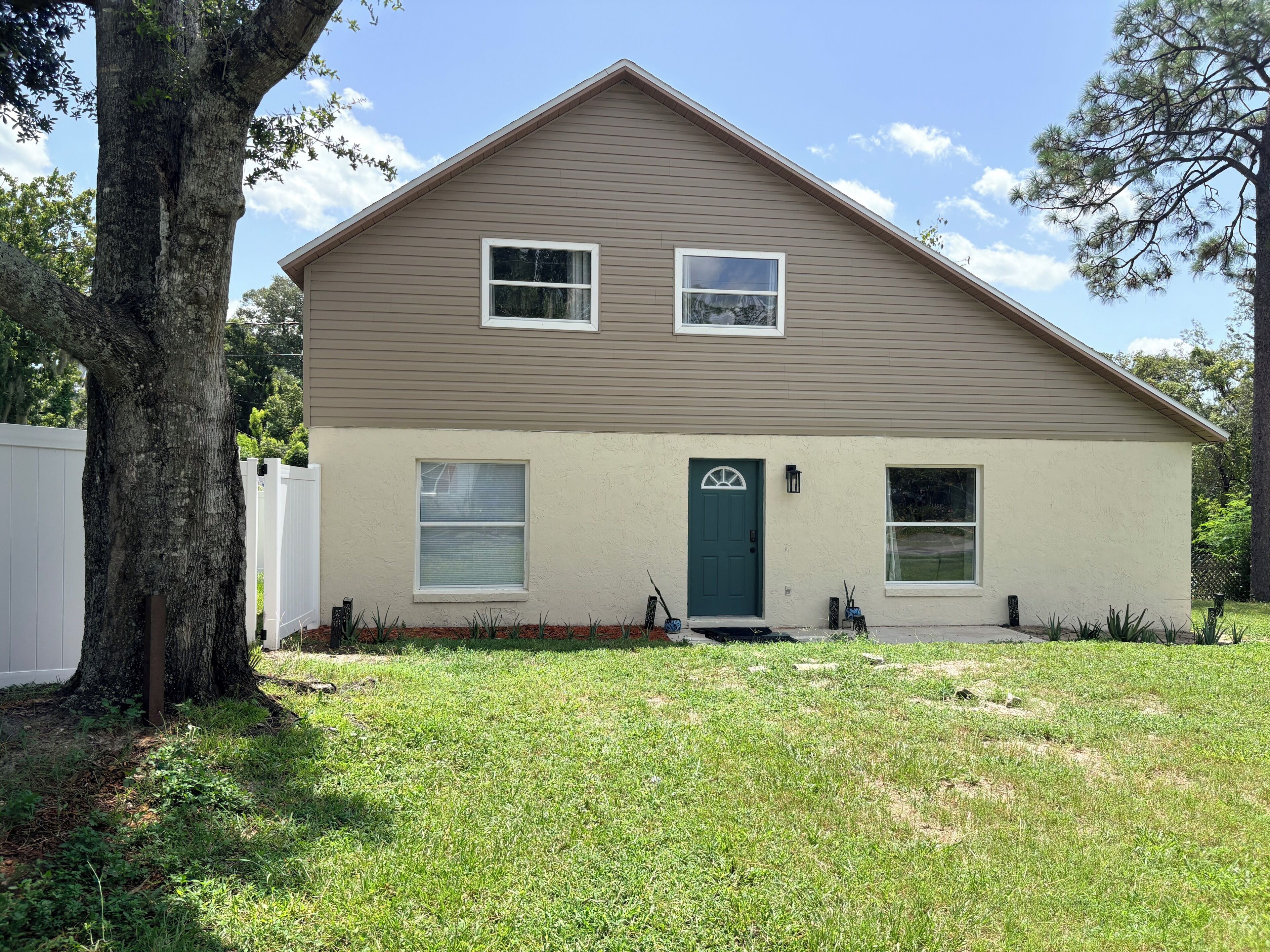 A two-story house with a front door, two windows on the upper floor, and a small front yard.