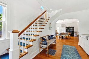 Ein großzügiger Wohnbereich mit einer Holztreppe, einem Essbereich und einer Couch.